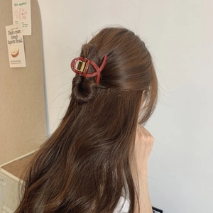 Close-up of a large deep red hair claw clip securing a half-up hairstyle on a model