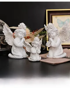 Macro detail of three praying resin cherub statues with intricate wing texture and matte finish