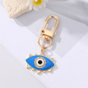 Golden evil eye keychain with blue enamel, rhinestones and eyelash geometric charms