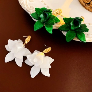 Detailed view of floral stud earrings with green and white resin petals and gold metal clasps