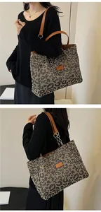 Detailed close-up of leopard print tote bag with brown leather handles and gold metal rings