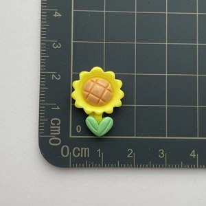 Detail view of small resin sunflower accessory with size scale on cutting mat