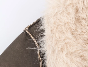 Detailed view of dark brown leather stitching and soft beige faux fur coat texture