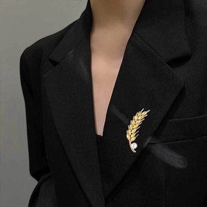 Detail of crystal wheat brooch with yellow stones and pearl on black blazer lapel