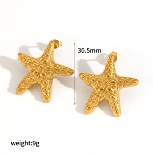Macro shot of gold starfish earrings featuring natural grain texture and size measurements