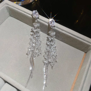 Close-up of silver long tassel earrings with sparkling crystals in a gray jewelry box