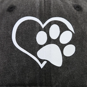 Detailed close-up of heart and paw print logo on black cotton baseball cap fabric