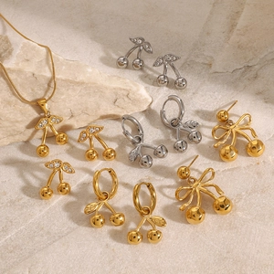 Golden and silver cherry jewelry set with bows and rhinestones on textured stone base