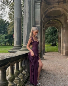 Detail of burgundy backless maxi dress with ruffle trim and side slit in garden setting