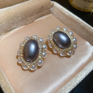 Detailed close-up of vintage gold stud earrings with grey and white pearls in a jewelry box