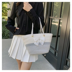 Detail of woven straw tote bag with white bow ornament and hemp rope handle