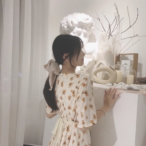 Detail of beige floral dress back featuring a large decorative bow tie on a model