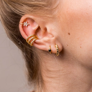 Detailed close-up of golden hoop earrings and studs with black and clear crystals