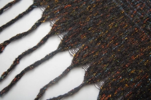 Macro shot of colorful knit fabric texture with twisted tassels on a fringe scarf