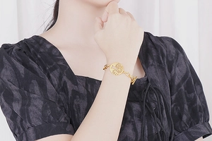 Detail of a gold Tree of Life charm bracelet with a vintage OT toggle clasp on a wrist