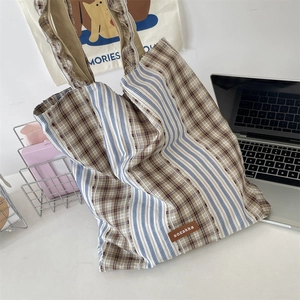 Detail of vintage plaid patchwork tote bag showing textured canvas fabric and leather label