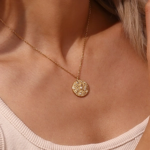 Collana dorata con ciondolo a stella in perla e zircone indossata da una modella