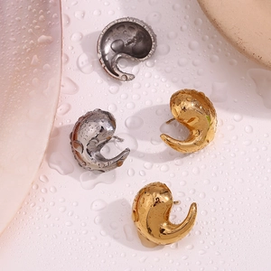 Detailed view of irregular teardrop earrings in 18K gold and silver finishes on water surface