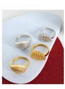 Macro shot of seashell-shaped gold and silver stainless steel rings with ribbed texture