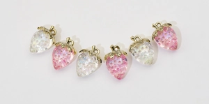 Macro shot of 6 iridescent strawberry charms in pink and white for DIY jewelry making