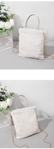 Detail of white faux fur tote bag featuring a chic golden metal chain shoulder strap
