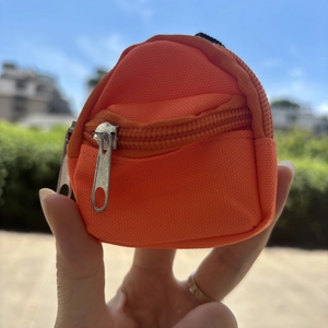 Handheld orange mini backpack coin purse made of durable canvas with silver zipper
