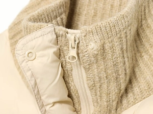 Close-up of knit ribbed stand-up collar and matching zipper on cream quilted jacket