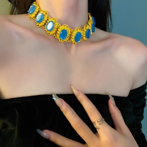Detail of vintage gold-rimmed choker with blue oval stones on a model's neck