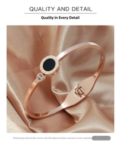 Detail shot of rose gold roman numeral bangle with black enamel on champagne silk background