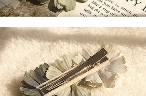 Detail showing the metal alligator clip and back of the fabric flower hair clip
