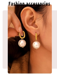 Close-up of elegant gold U-shaped earrings with large white pearls worn by a model