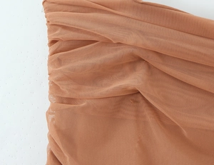 Détail macro du tissu en maille marron froncé avec texture superposée sur une robe