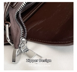 Detailed macro view of high-quality silver metal zipper on a dark brown leather shoulder bag