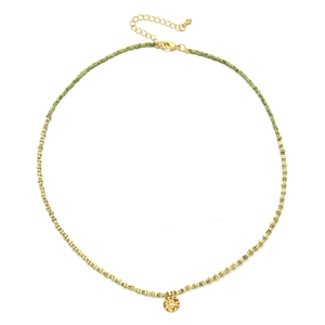 Detail of bohemian gold beaded necklace with green accents and textured round pendant
