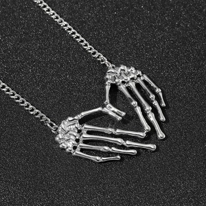 Gros plan d'un pendentif cœur formé de mains de squelette gothique sur une chaîne en métal