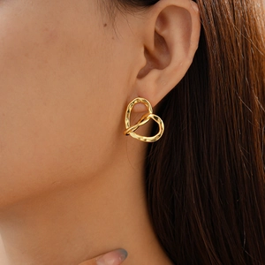 Detail shot of a 18k gold plated hollow twisted heart earring with hammered texture finish