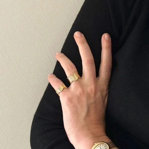 Close-up of elegant gold wave rings worn on a hand, featuring minimalist metal texture