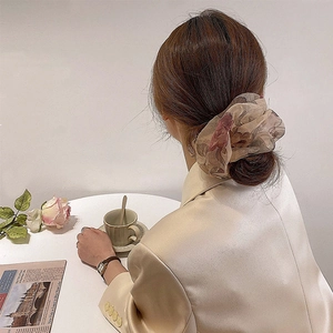 Detail shot of large champagne floral organza hair scrunchie styled in a high bun