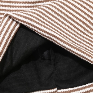 Macro detail of checkered waffle knit fabric with a soft black inner lining and brown stripes
