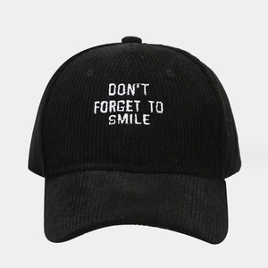 Close-up of white embroidery text on black corduroy texture of the baseball cap