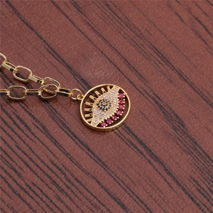 Macro detail of gold evil eye pendant necklace with red and black crystal stones