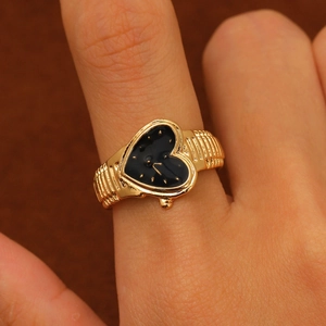 Close-up of vintage golden heart watch ring with black dial and gold hands on finger