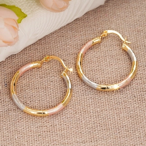 Three-tone gold hoop earrings with bamboo texture on a natural linen background