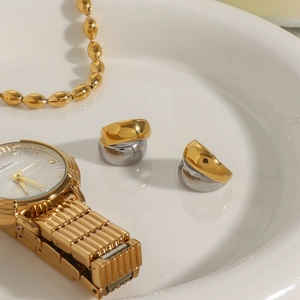 Detail of two-tone gold and silver teardrop ear cuffs on a white ceramic plate