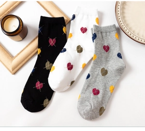 Detailed view of three pairs of cotton socks with colorful plaid heart patterns on white