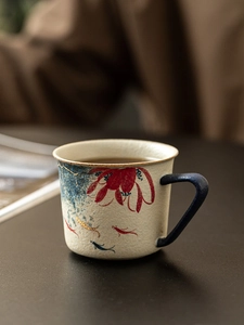 Macro detail of ceramic coffee mug featuring hand-painted red flowers and koi fish pattern