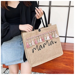 Detail view of large linen tote bag with colorful tassels and black mama print decoration