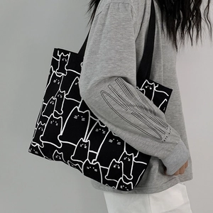 Detail of canvas tote bag featuring cute white cat patterns and matching small pouch