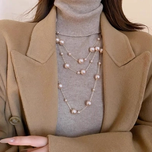 Gros plan détaillé d'un long collier de perles à trois couches aux reflets rose doré