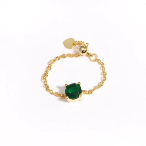 Detail of adjustable gold chain ring featuring a green zircon and heart pendant